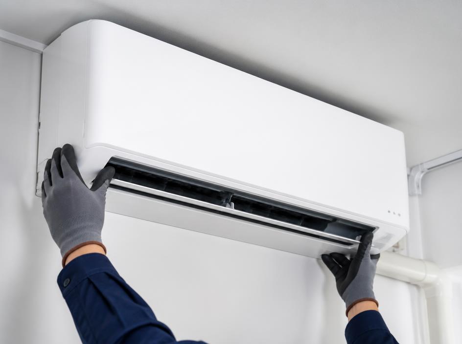 Técnico a instalar uma unidade interior de ar condicionado numa sala moderna
